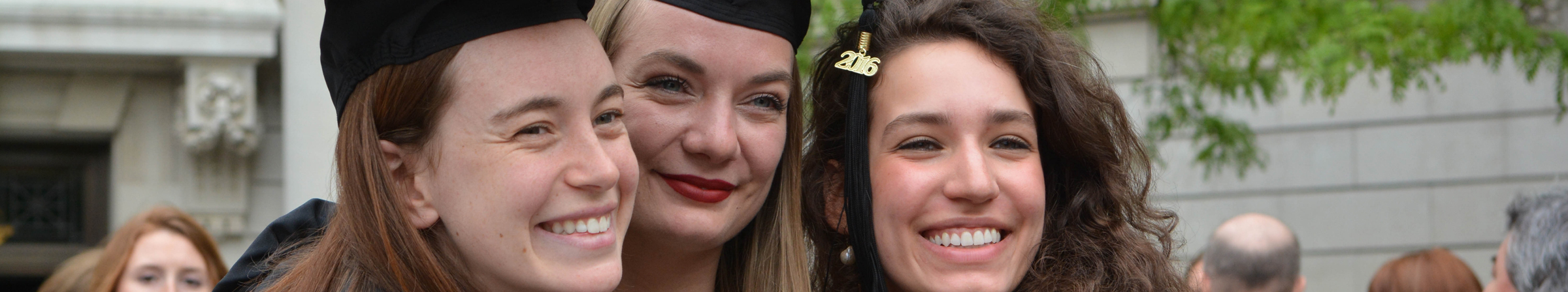Three graduates embracing and posing for a photo